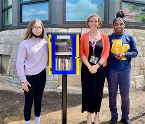 The artistic designers stand near the Free Little Library