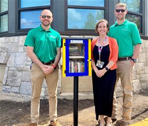  Teacher poses with Free Little Library. 